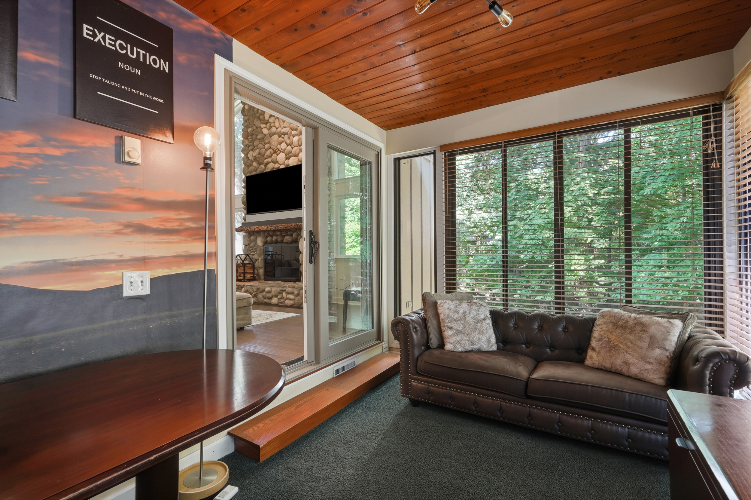 Wood-ceiling sunroom surrounded by windows and trees